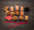 Philadelphia sushi roll with salmon and baked sushi with crab with ginger and soy sauce red chopsticks on wooden rustic backgr Royalty Free Stock Photo