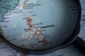 Philippines on a world map through magnifying glass.