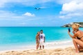 Couple pose for photo on beach with aircraft landing behind