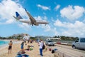 Philipsburg, Sint Maarten - February 13, 2016: airplane land over people on maho beach. Plane low fly on cloudy blue sky. Jet flig Royalty Free Stock Photo