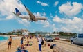 Philipsburg, Sint Maarten - February 13, 2016: airplane land over people on maho beach. Plane low fly on cloudy blue sky Royalty Free Stock Photo