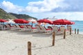 Philipsburg, St. Martin - 1/23/18: Beach umbrellas and lounge chairs along the beach and the Carnival Conquest cruise ship docked Royalty Free Stock Photo