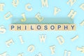 Philosophy concept. Word spelled in wooden blocks on blue background.