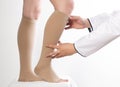 The phlebologist doctor selects the size of the patient`s compression stockings. White background, close-up