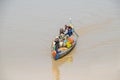 Long-tail Mekong boat with a Cambodian family manoevring it on to the coast of the Mekong river