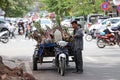 Cambodian man standing with his three wheels motorcycle carrying sugarcane to be delivered on the street