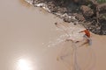 A fisherman throwing a net into the river for fishing in Phnom Penh