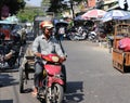 Cambodian male ride the three wheels motorcycle carrying glass cabinets to be delivered on the street