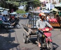 Cambodian male ride the three wheels motorcycle carrying glass cabinets to be delivered on the street