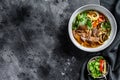 Pho Bo Vietnamese fresh rice noodle soup with beef, herbs and chili. Black background. Top view. Copy space