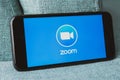 Phone on blue sofa showing Zoom Cloud Meetings app.
