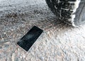 Phone with broken screen on snow in car trails