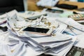 phone buried under papers on a disorganized office table