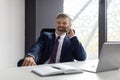 Phone Call. Smiling Mature Businessman In Suit Talking On Cellphone At Workplace Royalty Free Stock Photo