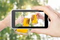 On the phone the Clinking Beer glasses on blurred background. Royalty Free Stock Photo