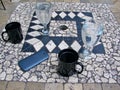 Phone and coffee mugs and glasses of water on tiled table top