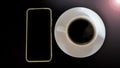 Phone and a cup of black coffee on white plate on the table with light. Top view. Business table flat lay concept. Royalty Free Stock Photo