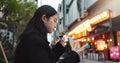 Phone, eating and Asian woman with onigiri in the city on exploring vacation, adventure or holiday. Hungry, food and