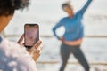 Phone, fitness and photograph of woman at beach in silly pose at sea for senior friends. Exercise, mobile and picture