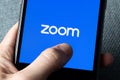 Phone with a hand showing Zoom Cloud Meetings app. Royalty Free Stock Photo