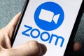 Phone with a hand showing Zoom Cloud Meetings app. Royalty Free Stock Photo