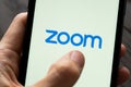 Phone with a hand showing Zoom Cloud Meetings app. Royalty Free Stock Photo