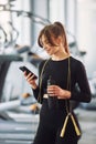 With phone in hands and jump rope on the neck. Young beautiful woman in sportive clothes have fitness day in the gym Royalty Free Stock Photo