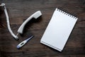 Phone handset, thermometer and notebook on dark wooden desk top view call doctor mock up