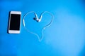 Phone and heart-shaped headphones on an isolated blue background Royalty Free Stock Photo