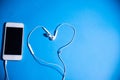Phone and heart-shaped headphones on an isolated blue background Royalty Free Stock Photo