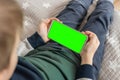 Phone a for keying is holding kid. Smartphone with a green screen in hand child top view close up Royalty Free Stock Photo