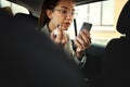 Phone, lipstick and a business woman in a taxi to travel in the city for work while multitasking. Face, mobile and Royalty Free Stock Photo