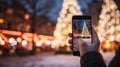 phone in man hand making photo of festive colorful Christmas tree and snowman in winter snowy city Royalty Free Stock Photo