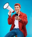 Phone, megaphone and young man in a studio reading announcement or speech for a rally. Happy, cellphone and male