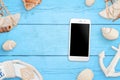 Phone mockup on blue wooden table surrounded with sea shells, anchor, boat life belt