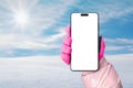 Phone mockup in hand with pink glove. Snow and sun in the background