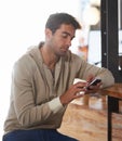 Phone, networking and young man in a cafe on social media, mobile app or the internet at table. Technology, reading and Royalty Free Stock Photo
