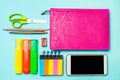 Phone, notebook, pen, scissors, colored markers, pencil, sticky stickers, sharpener on the school desk. back to school. blue backg