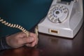 Phone old retro, old fashioned white telephone against green background, woman hand holding telephone cord
