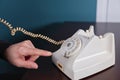 Phone old retro, old fashioned white telephone against green background, woman hand holding telephone cord in long Royalty Free Stock Photo
