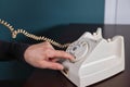 Phone old retro, old fashioned white telephone against green background, woman hand holding telephone cord