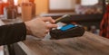 Phone payment close-up of a customer attaching a smartphone to a payment terminal to pay for coffee in a cafe. Royalty Free Stock Photo