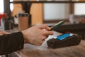 Phone payment close-up of a customer attaching a smartphone to a payment terminal to pay for coffee in a cafe. Royalty Free Stock Photo