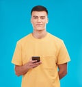 Phone, portrait and young man in studio networking on social media, mobile app or internet. Smile, technology and male