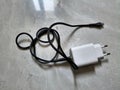Phone power supply with black USB cable roll on patterned marble floor Royalty Free Stock Photo