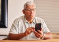 Phone, social media and a senior man in his home, reading or typing a text message for communication. Mobile, contact Royalty Free Stock Photo