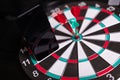 Phone stands on Darts field with Three Darts to hit red target close-up