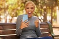 Phone, success and woman excited about trading on the internet while on a bench in the park. Young, happy and girl with