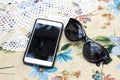 Phone on the tablecloth with flowers. Lace napkins and glasses Royalty Free Stock Photo