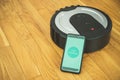 Phone to control robotic vacuum cleaner. Royalty Free Stock Photo